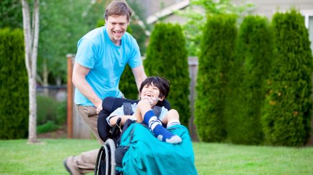 bambino con padre su sedia a rotelle