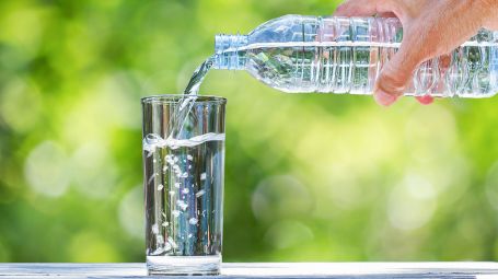 acqua minerale versata da una bottiglia in un bicchiere