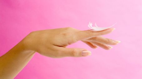 mano donna con una piuma bianca su dito indice