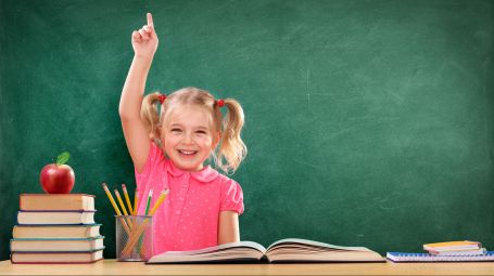 bambina sorridente che alza la mano a scuola