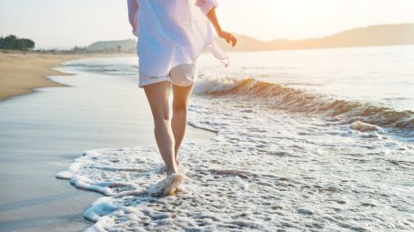 donna cammina sulla spiaggia, al mare