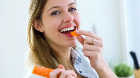 donna sorridente e felice mangia carota