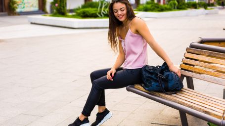 donna in città seduta su panchina con la borsa