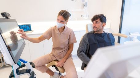 Dentista che mostra l'immagine 3D al paziente seduto su una sedia, intelligenza artificiale