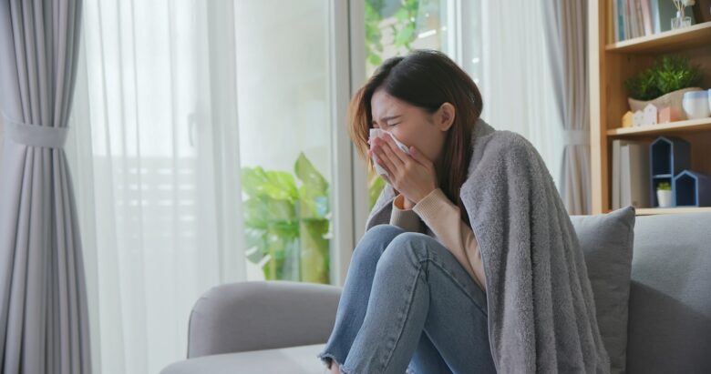 donna sul divano si soffia il naso per il raffreddore
