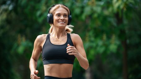 donna matura corre nel parco con cuffie musica, runner