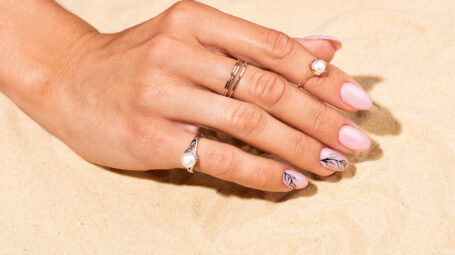 mano nella sabbia, anelli, smalto, unghie