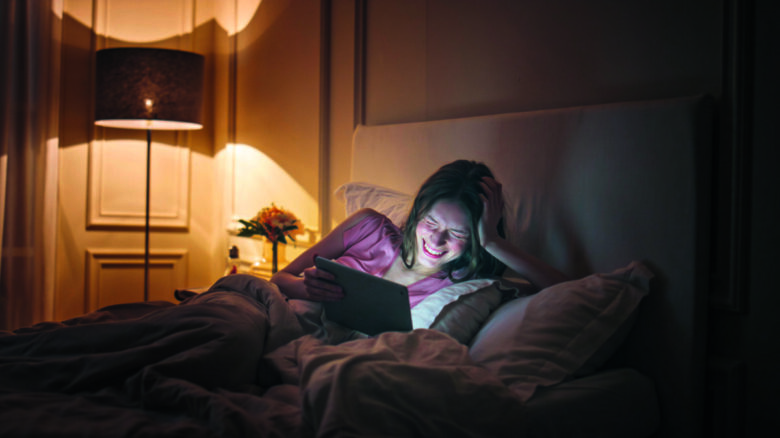 ragazza a letto felice guardando il computer