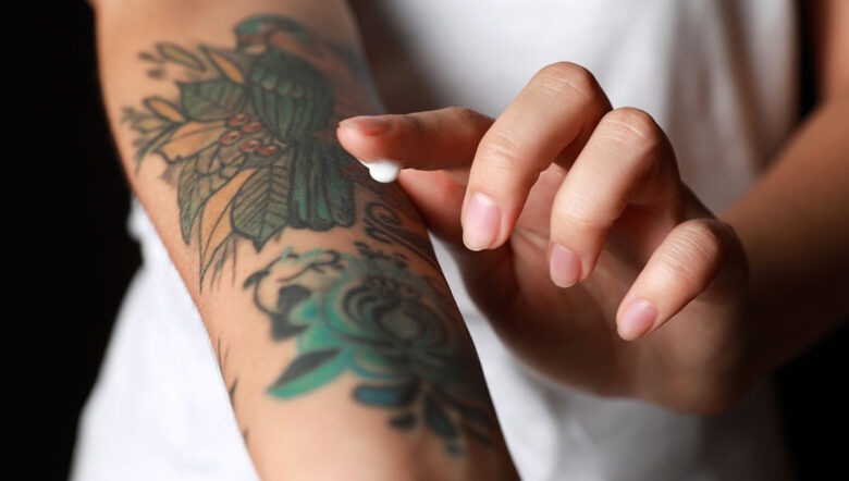 tatuaggio sul braccio di una donna che si mette una crema