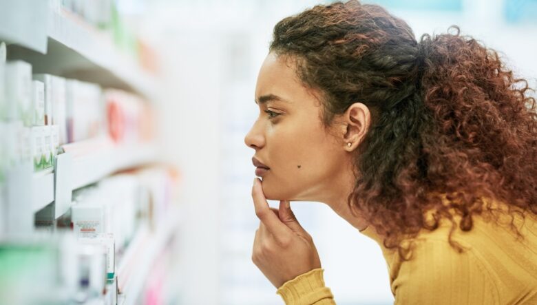 donna in farmacia davanti a scaffale di integratori