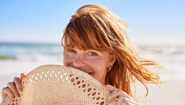 ragazza dai capelli rossi al mare con un capello