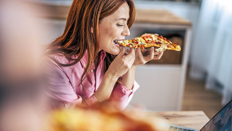 ragazza mangia pizza davanti al computer