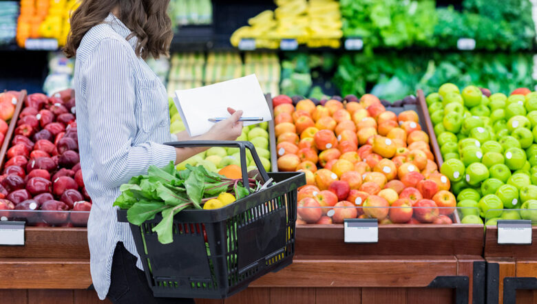 donna al supermercato davanti a banco della frutta e verdura