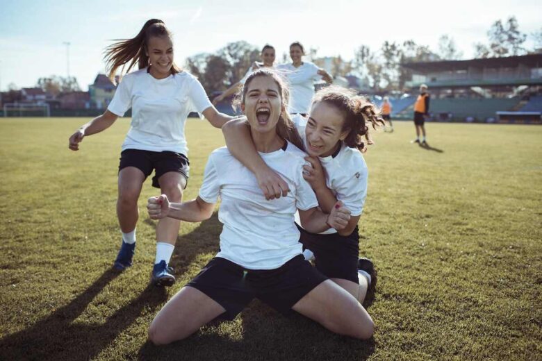 tre ragazzine esultano su un campo da calcio