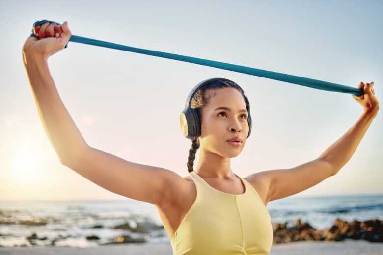 ragazza fa ginnastica con una banda elastica su una spiaggia