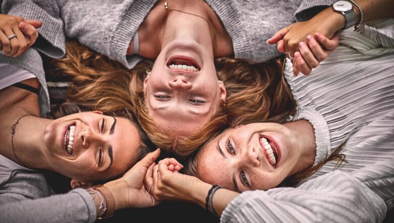 tre amiche sorridenti si tengono per mano