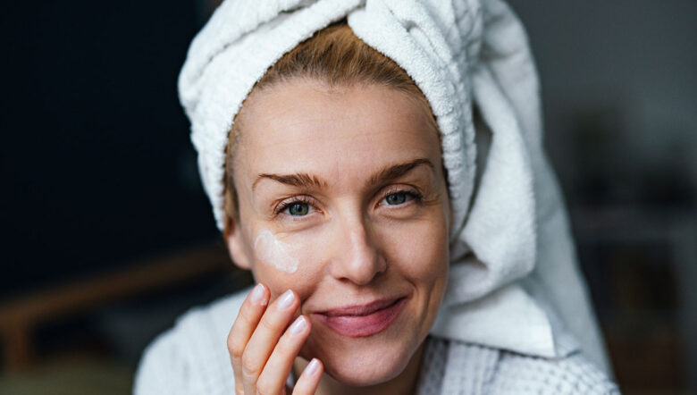 donna sorridente che applica la crema idratante al mattino