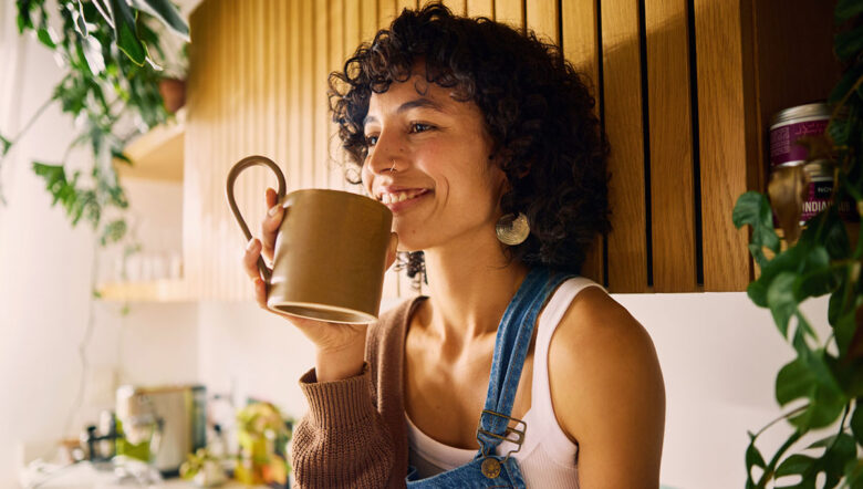donna sorridente e relax con tazza in mano in cucina