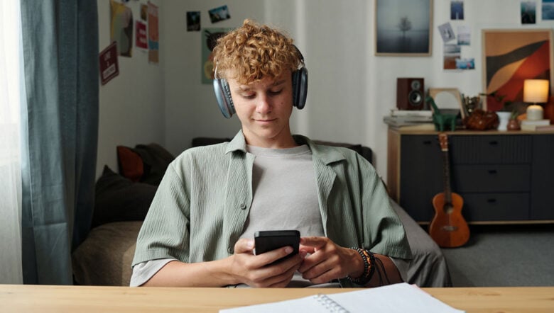 studente a casa con i compiti da fare e il cellulare