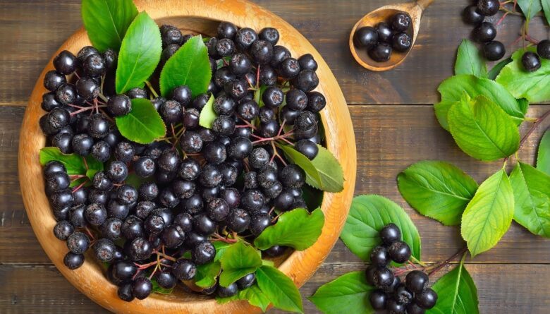piatto di legno pieno di bacche di aronia