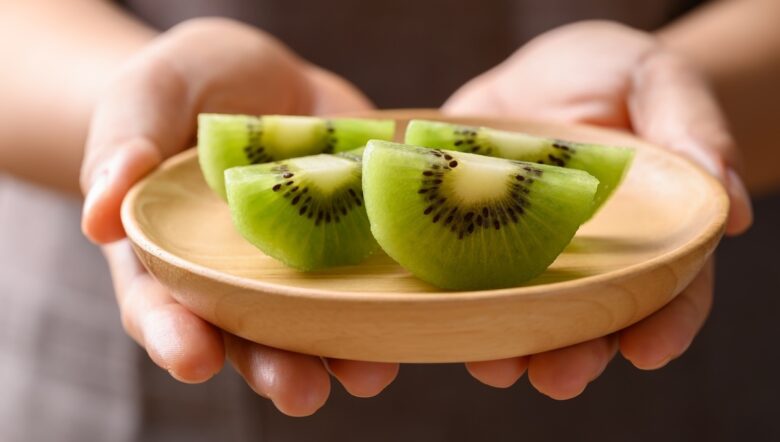 mani offrono kiwi su piattino legno