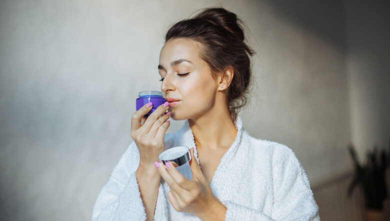 ragazza in bagno che annusa la crema per il viso