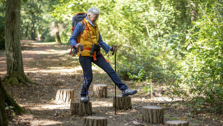 donna salta sui tronchi tagliati degli alberi nel bosco